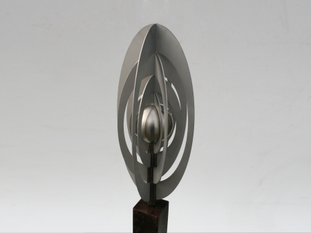 Stainless steel display of a metal ball surrounded by blades of metal sheets, placed on a freestone pedestal. Afmeting: 148 x 20 x 20 cm. series of 2 pieces sold out